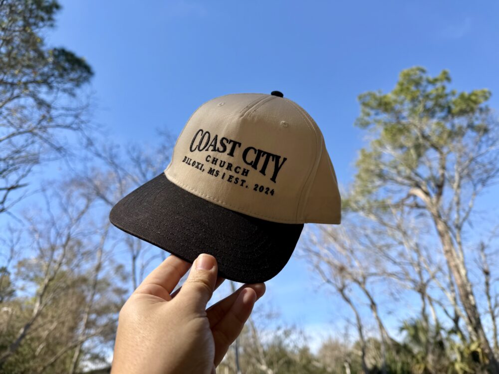 Coast City Hat being held towards the blue sky.